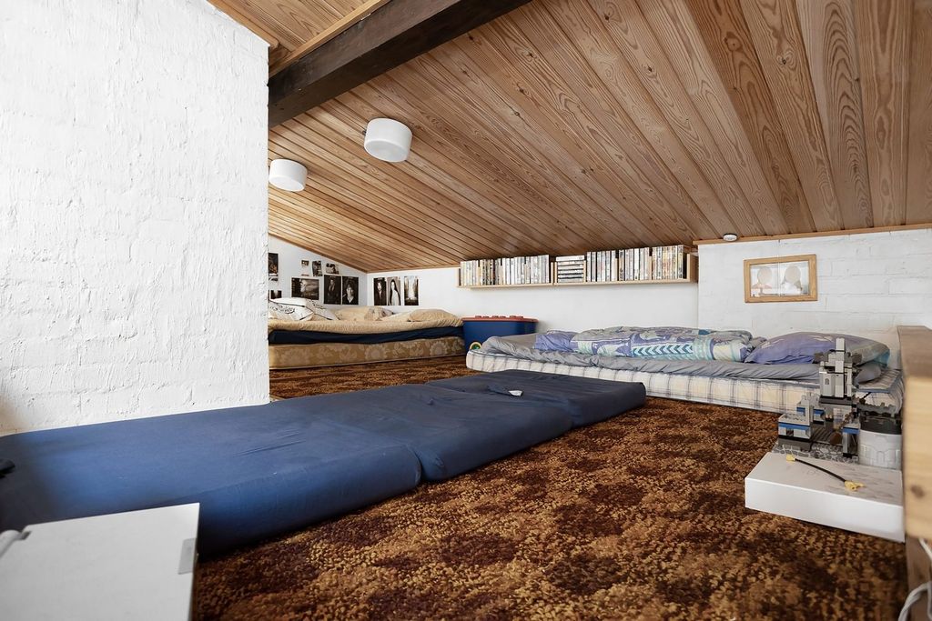 Couchage en mezzanine sous une charpente bois.