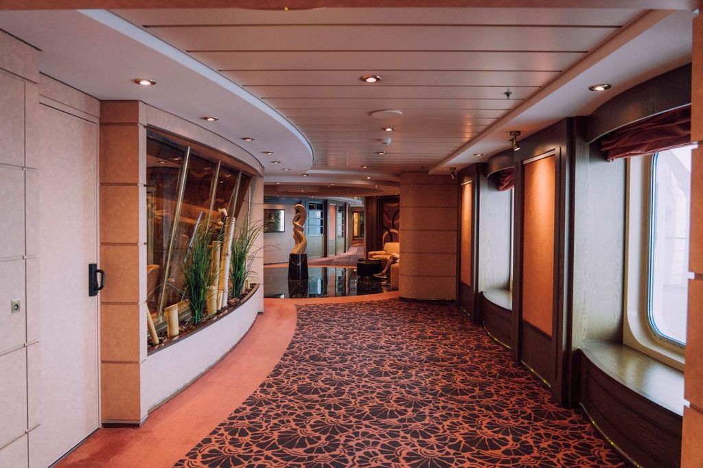Coursive d’un navire de croisière : boiseries, moquette et éclairages intégrés.
