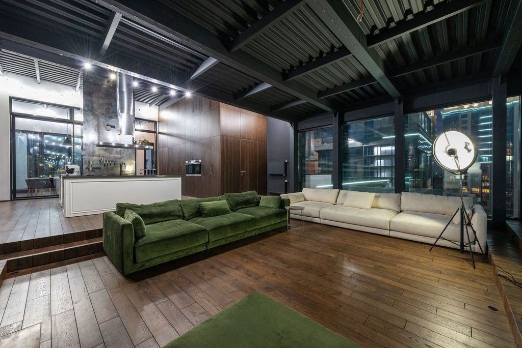 Loft industriel : structure métallique, grandes baies et sol en bois.