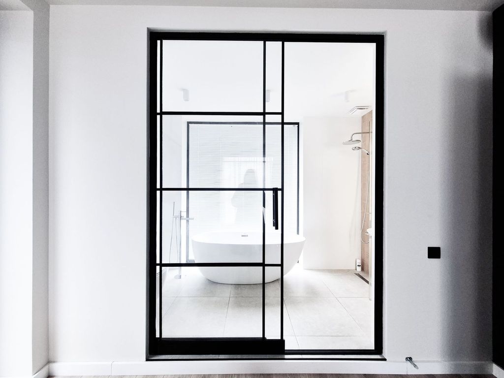 Porte vitrée à cadre en acier noir, dans l’esprit des menuiseries d’atelier.
