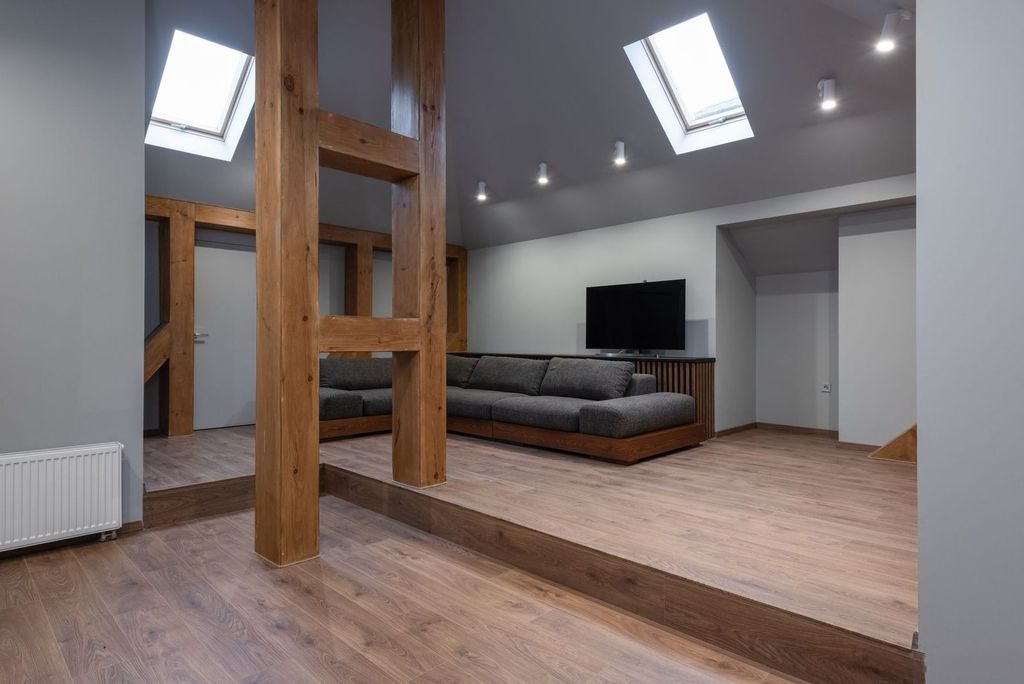 Poteaux et poutres en bois apparents sous les combles : l’esprit loft dans une maison en bois.