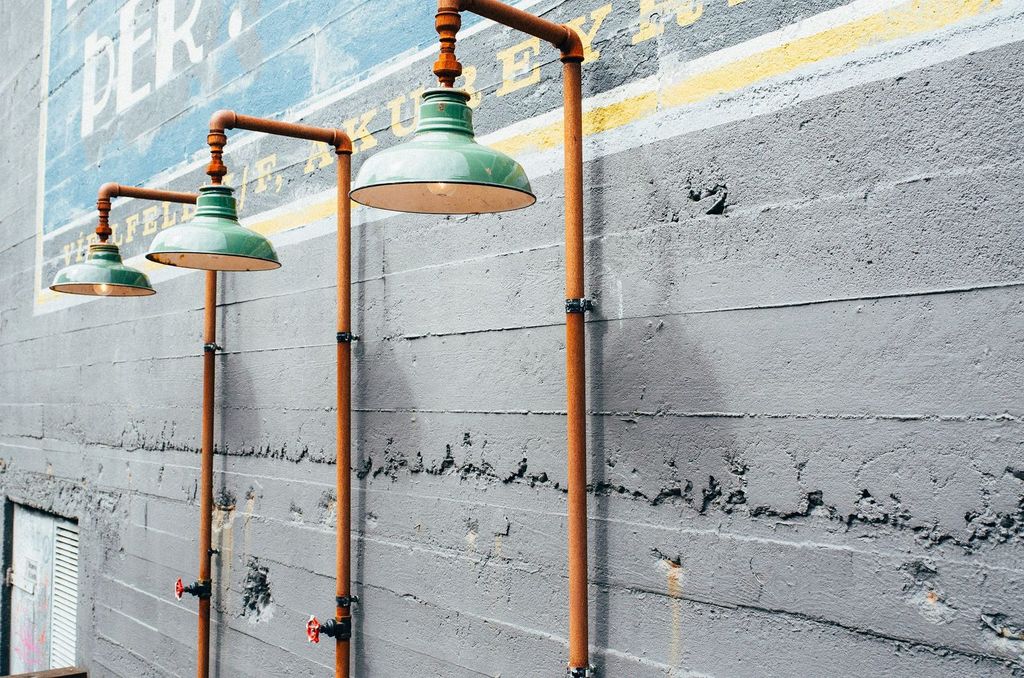 Réseaux et luminaires apparents sur un mur de béton brut.