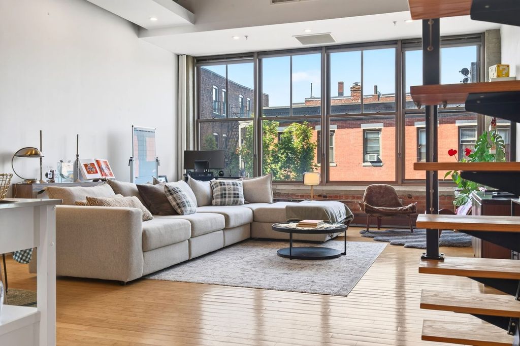 Séjour d’un loft rénové : grandes fenêtres et escalier ouvert.